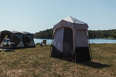 A Bushnell Shower Tent with Instant Setup Technology sitting on top of a grass-covered field.