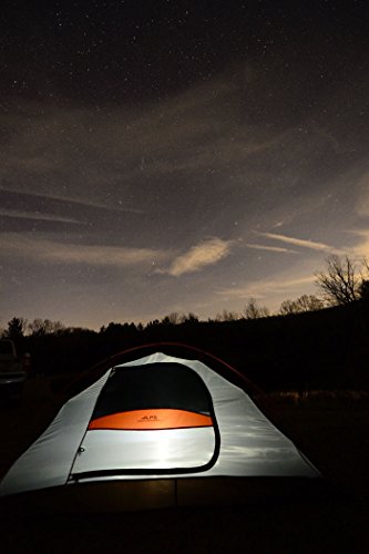 tent at night lit up with starry sky with some clouds