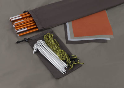 poles in bag before assembly spikes and ropes with bag underneath pieces of tent fabric three colors