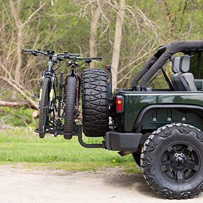 A green jeep with a KAC KR-BRDUBK Heavy Duty K2 Sport 2 Inch Hitch Rear Mounted 2-Bike Bike Rack with Locking Hitch Pin, Smart Tilt Feature, and 120 Pound Capacity, Black on the back of it.