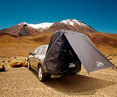 A HASIKA Tailgate Shade Awning Tent for Car Camping Road Trip Essentials Midsize to Full Size SUV Van Waterproof 3000MM UPF 50+ Black (Large) on top of a car in the desert.