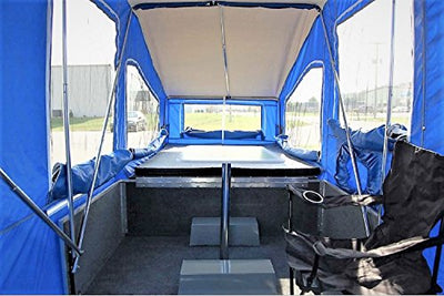 The back of a Time Out Trailers' Deluxe Camper with a table and chairs in it.