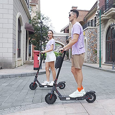 A man and a woman standing on a Hiboy S2 Pro Electric Scooter with Seat, 500W Motor, 10" Solid Tires, 25 Miles Long-Range & 19 Mph Folding Commuter Electric Scooter for Adults with Dual Rear Suspension by Hiboy.
